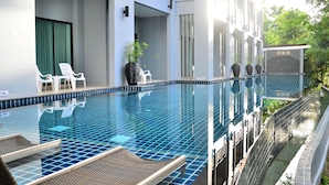 Une piscine avec des chaises longues, une plante en pot et une vue sur la verdure.