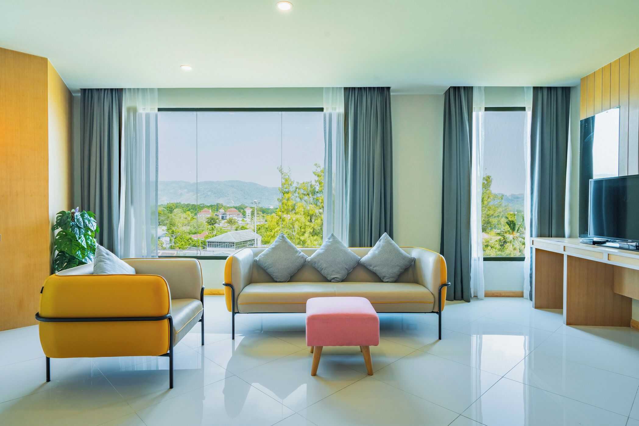 A modern living room with a sofa, ottoman, and a TV.