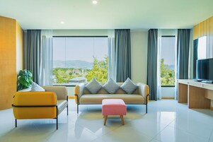A modern living room with a sofa, ottoman, and a TV.