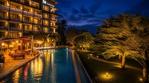 A hotel with a swimming pool, outdoor seating, and well-lit surroundings. - The Par Phuket (Kathu)