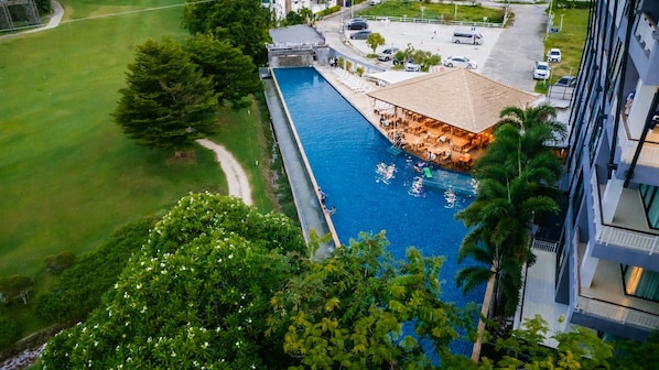An aerial view of a hotel with a swimming pool, outdoor seating area, and a parking lot.