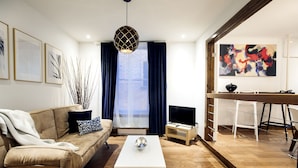 A modern living room with a sofa, coffee table, and a TV. There is a dining area with a bar stool and a painting on the wall. - Loft Jacques-Cartier- Le Plateau Free Parking (Montreal)