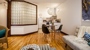 A living room with a wooden floor, a sofa, a dining table with chairs, and a kitchen in the background. - Loft Jacques-Cartier- Le Plateau Free Parking (Montreal)
