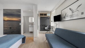 Ein modernes Hotelzimmer mit einem Bett, einer Couch, einem Fernseher und einem Vogelbild.