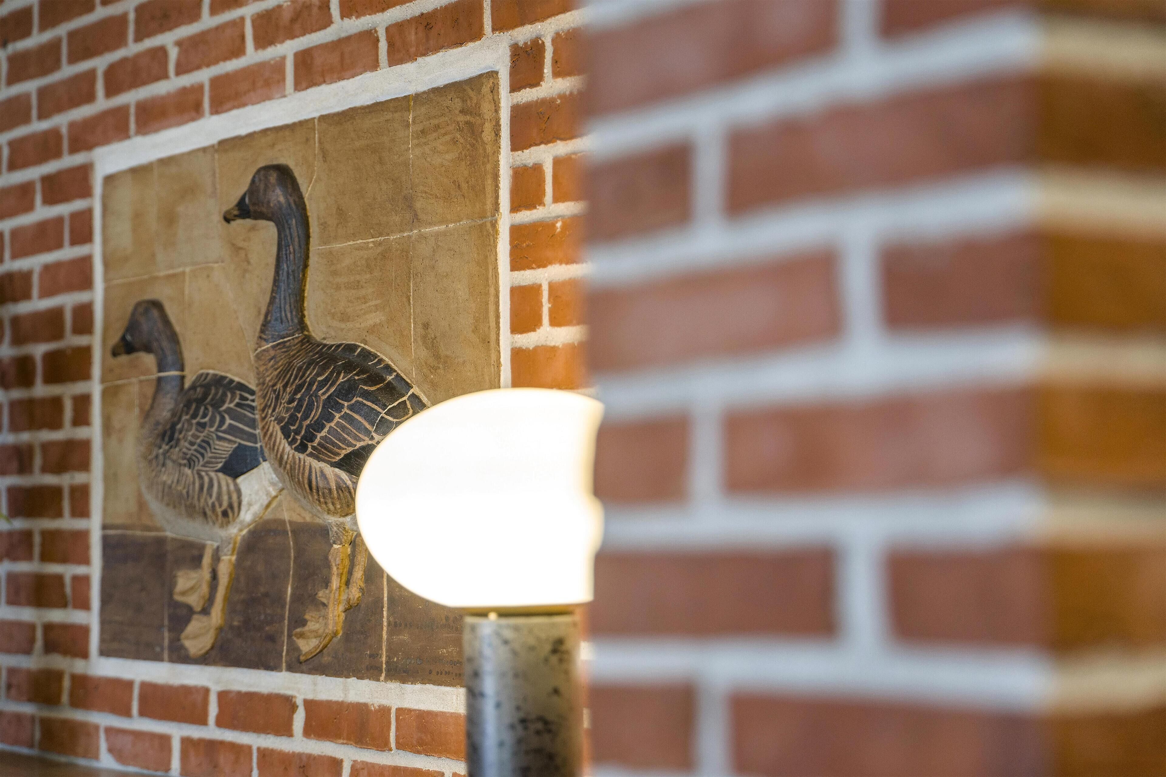A mural of two geese on a brick wall.