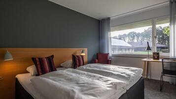 Een hotelkamer met een groot bed, een bureau, een stoel en uitzicht op buiten.