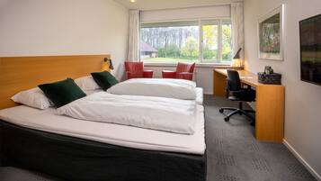 A hotel room with a large bed, a desk, and a chair.