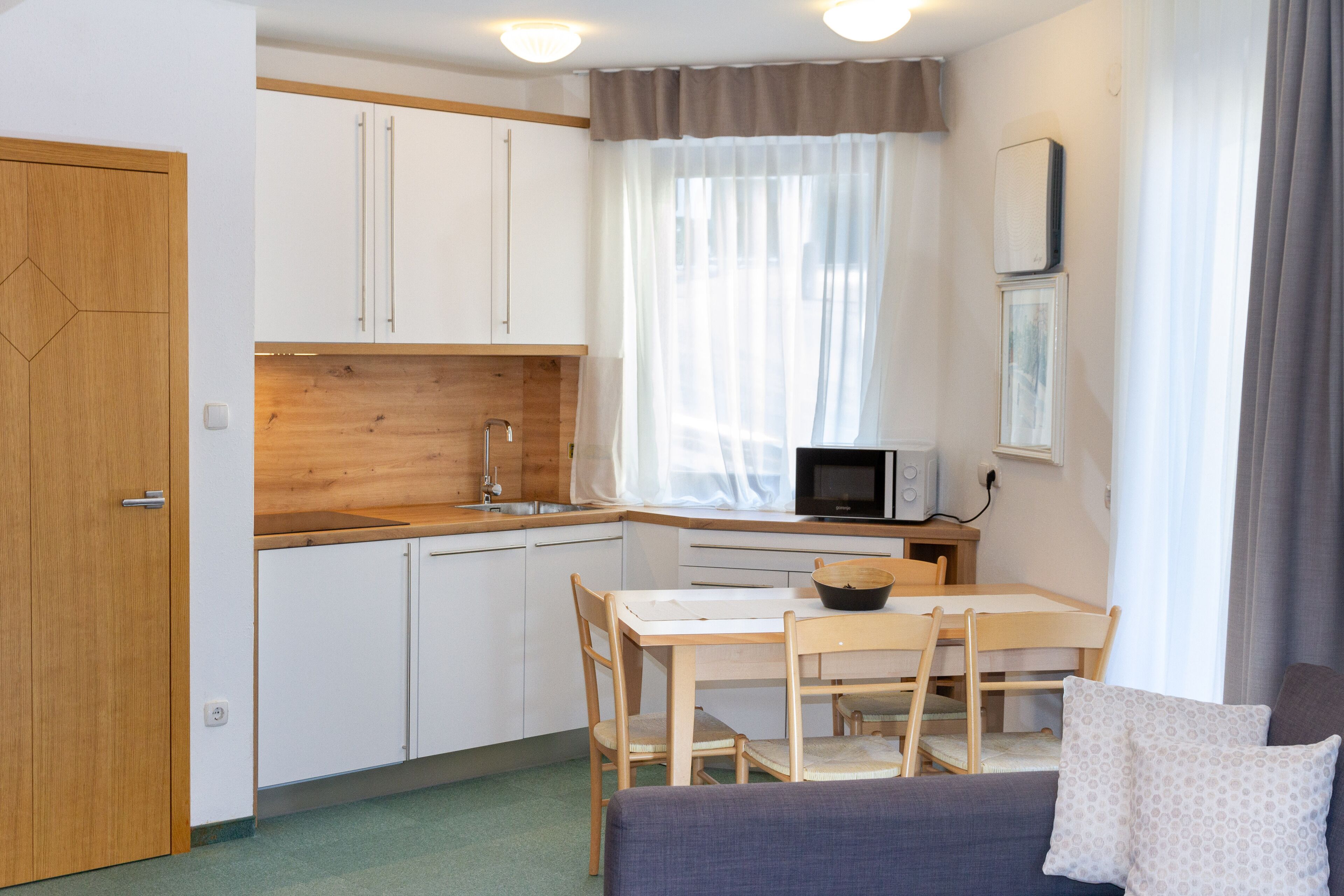 A compact kitchen with white cabinets, a wooden countertop, and a dining area with a table and chairs.