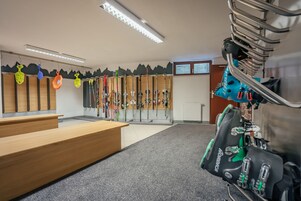 Zona de alquiler de esquíes con bancos de madera y esquíes en estanterías.