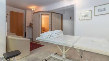 examination room with a white examination table, cushioned headrest, and footrest, accompanied by a stool and a couch.
