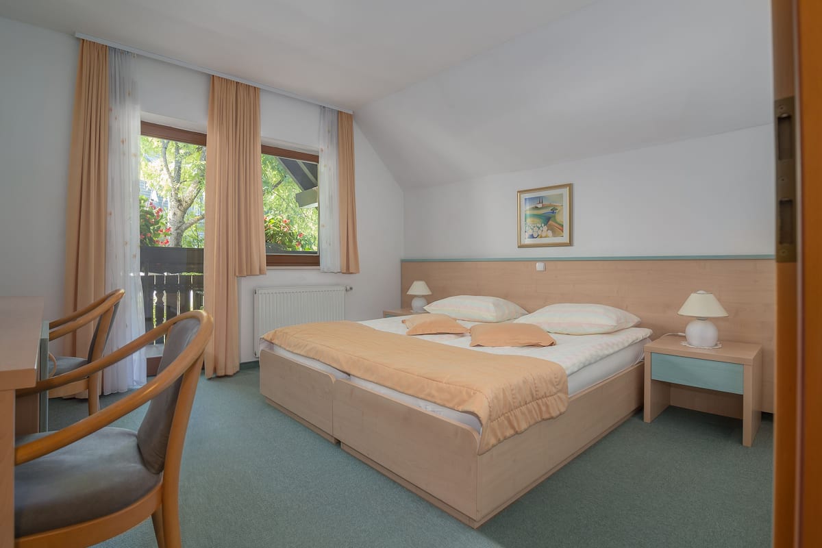 A bedroom with a bed, bedside tables, a chair, and a window with curtains.