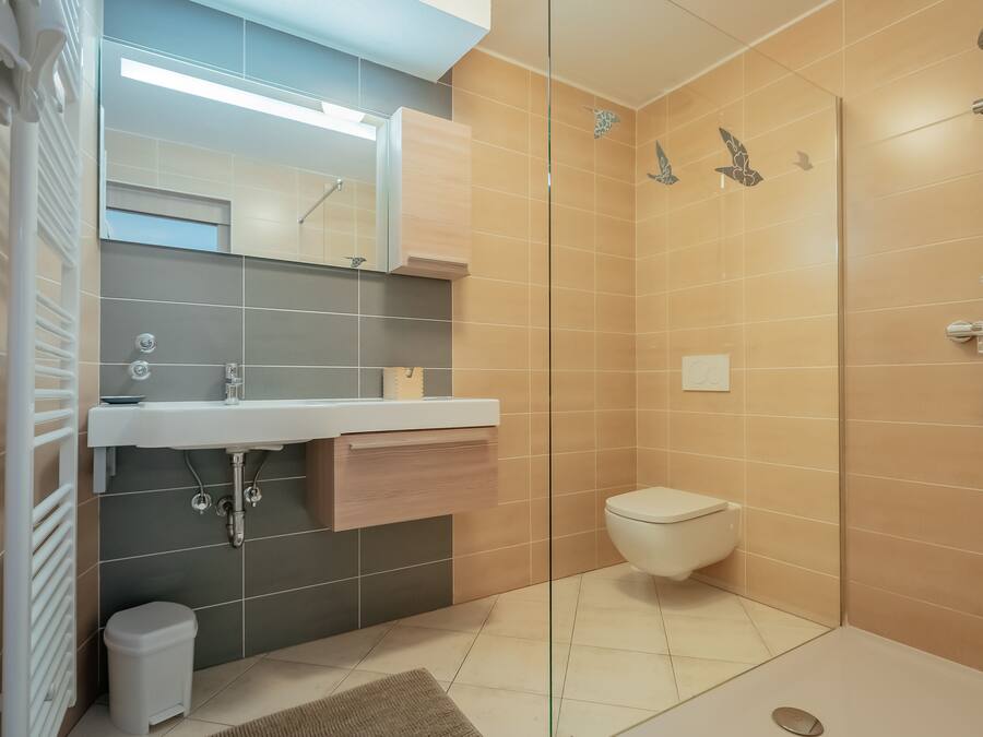 Un baño moderno con cabina de ducha de vidrio, lavabo blanco y retrete.