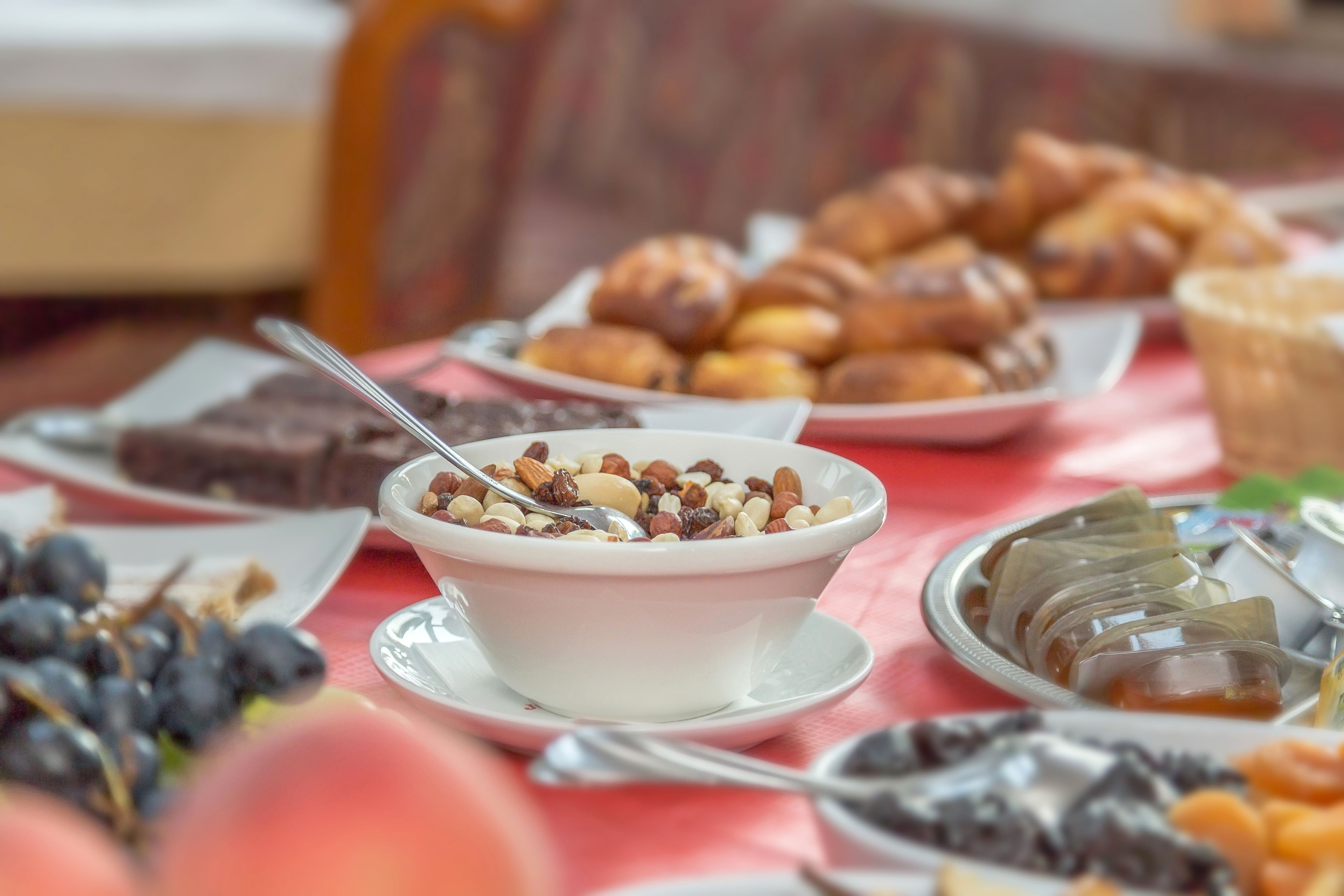 Une table sur laquelle on trouve divers aliments, notamment un bol de céréales avec des noix, des pâtisseries et d’autres en-cas.