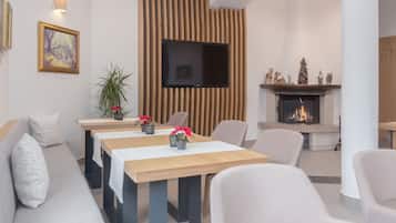 Una moderna hall d'hotel con una lunga reception in legno, posti a sedere confortevoli, una TV a schermo piatto e un caminetto.