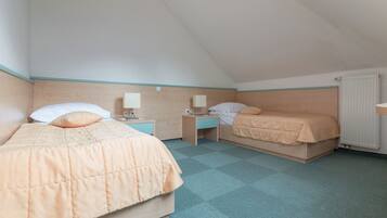 Una habitación con dos camas, cabecero de madera, radiador y suelo a cuadros.