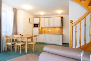 Habitación de hotel compacta con zona de comedor, kitchenette y escalera.