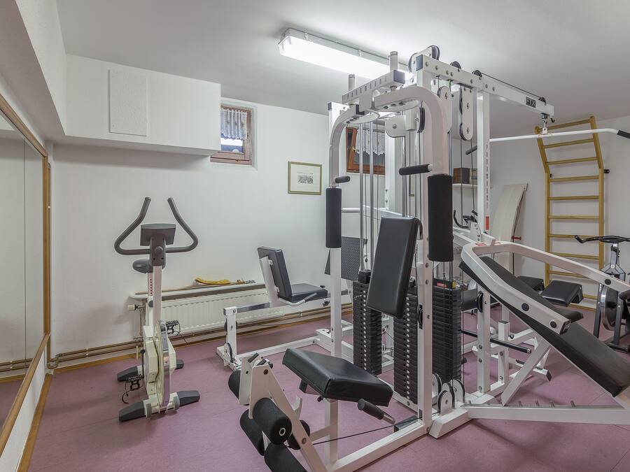 Un gimnasio con equipo de ejercicio, un espejo y una ventana con cortinas.