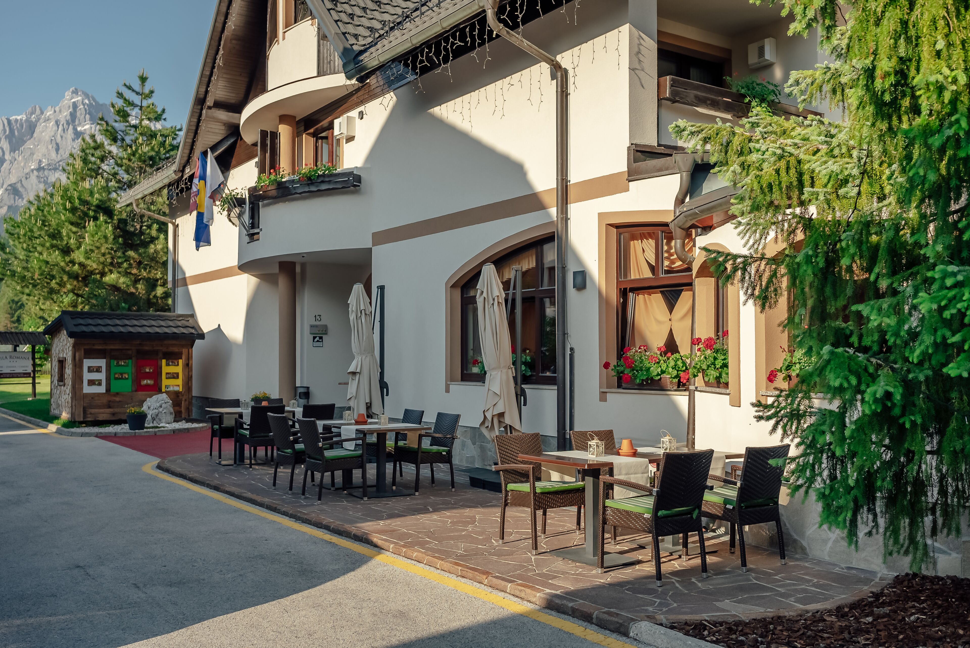 A building with outdoor seating, a small shop, and a mountain view.