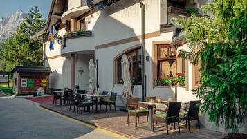 A building with outdoor seating, a small shop, and a mountain view.