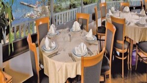 A restaurant with tables set for dining, overlooking a coastal view. - San Simon Resort Dependences (Izola)