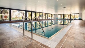 An indoor swimming pool with clear glass walls, metal pool ladders, and a tiled floor. - San Simon Resort Dependences (Izola)
