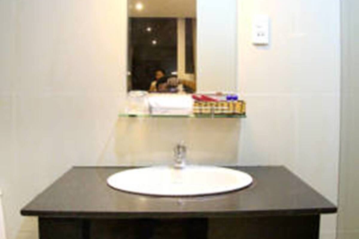 A bathroom with a dark countertop sink, a mirror, and a towel rack.
