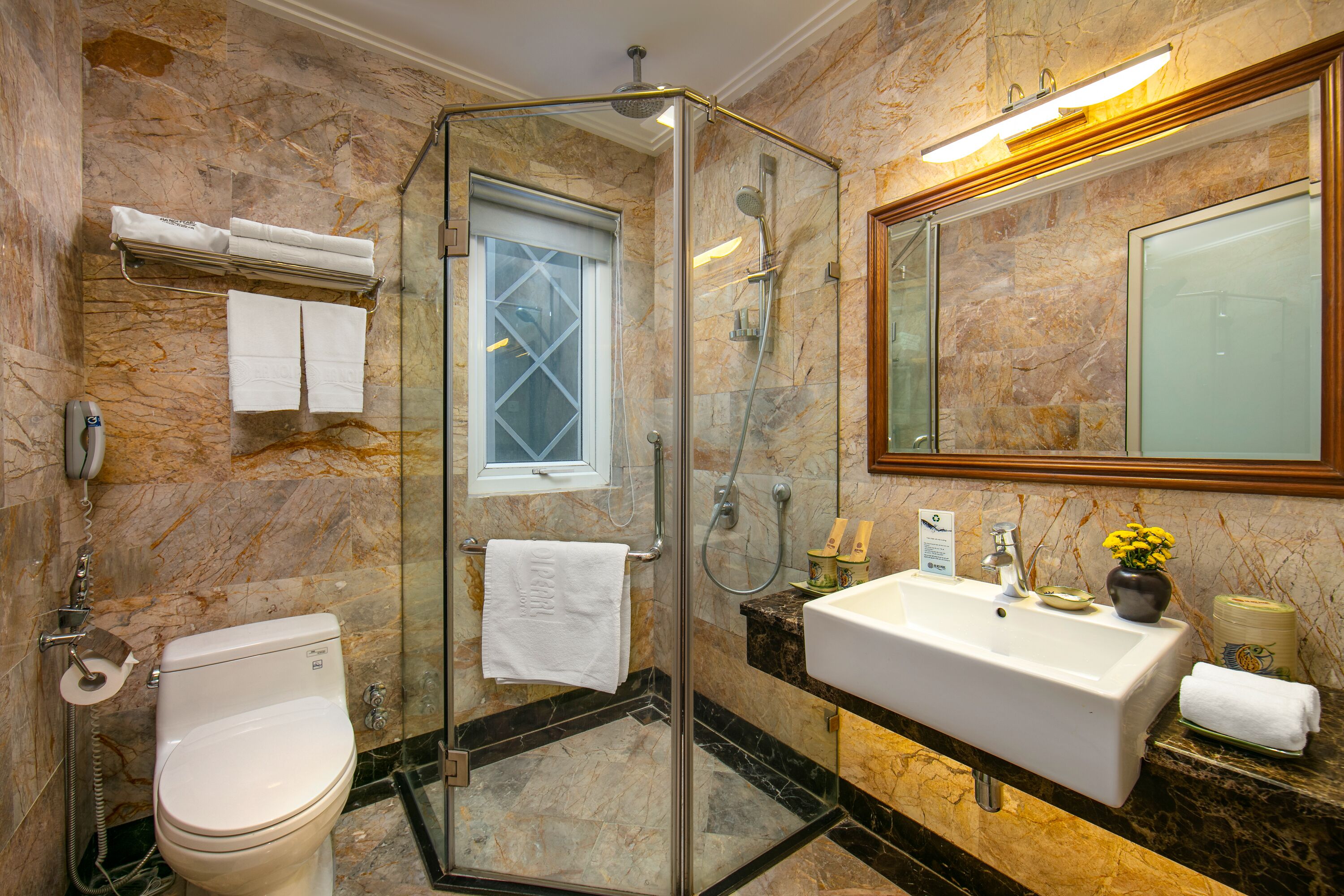 A bathroom with a glass-enclosed shower, a toilet, a sink, and a large mirror.