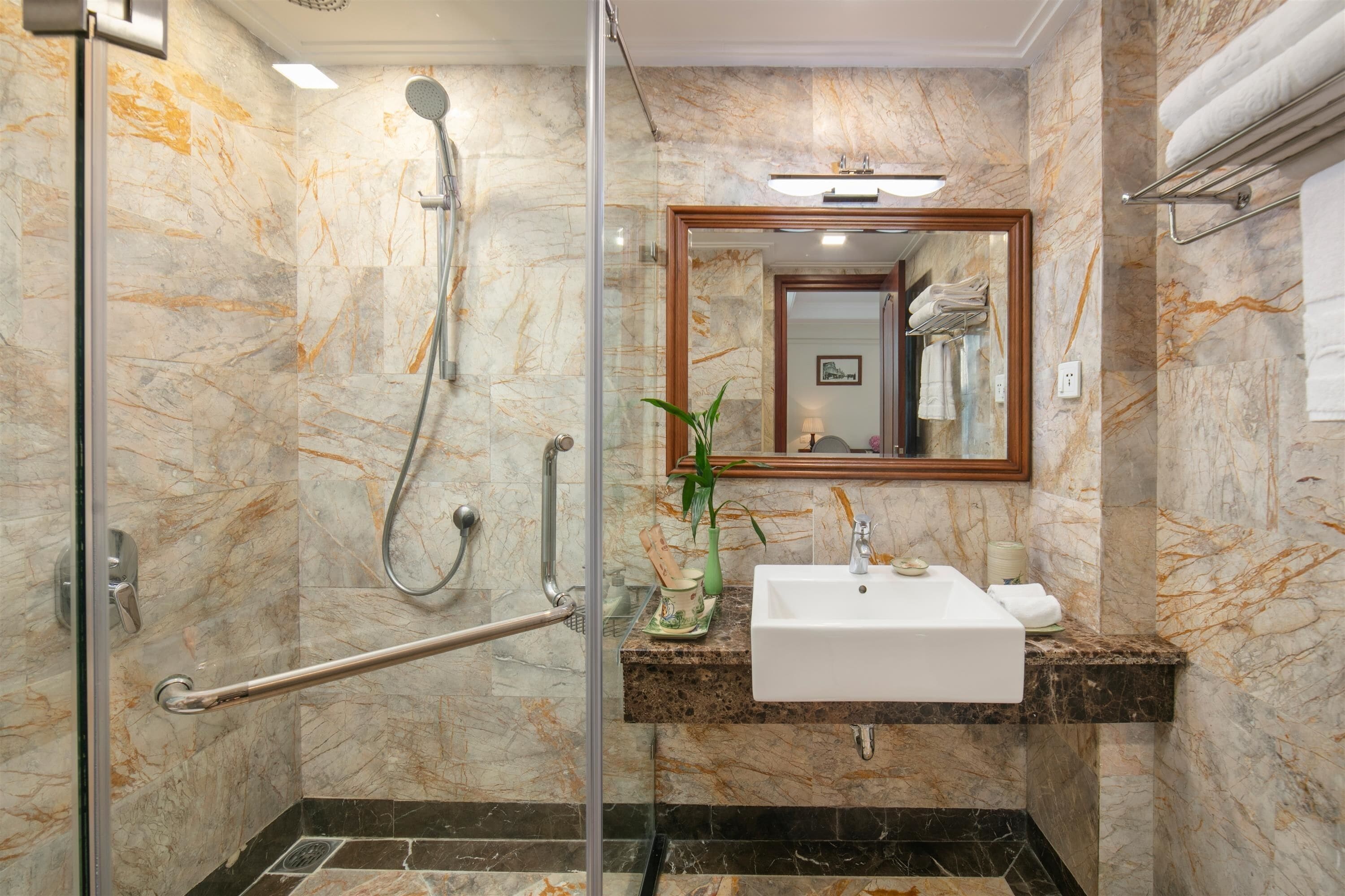 Un baño moderno con ducha de vidrio, un lavabo y pared con azulejos de mármol.