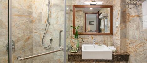 Un baño moderno con ducha de vidrio, un lavabo y pared con azulejos de mármol.