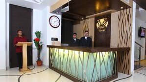 A reception desk with a clock, reception area, and a potted plant. - Hotel Tigers Roare' (Peermade)