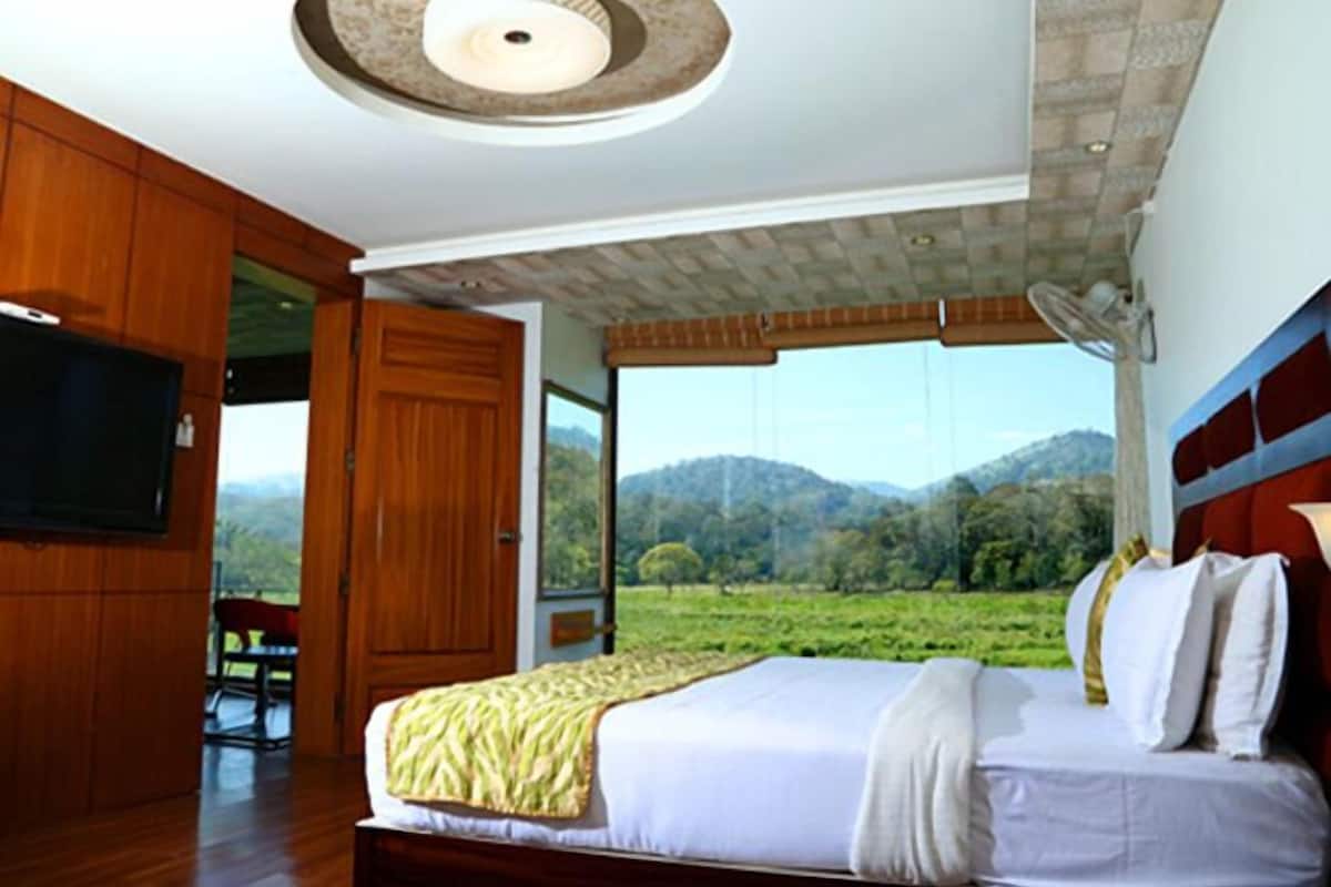 A bedroom with a large bed, wooden wardrobe, and a TV.