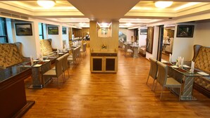 A spacious hotel lobby with a long reception desk, multiple seating areas, and framed artwork on the walls. - Hotel Tigers Roare' (Peermade)