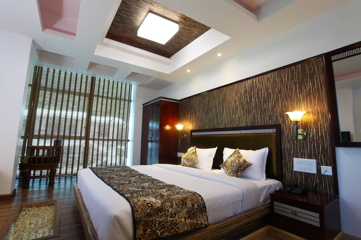 A hotel room with a large bed, a wooden headboard, a nightstand, a mirror, and a skylight.