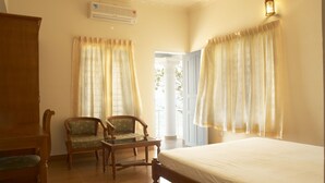 A room with a bed, two chairs, a small table, and a window with curtains. - Sealine Beach Resort (Kochi)
