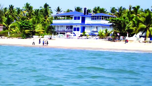 A two-story building with a blue roof and white walls, located on a beach with palm trees. - Sealine Beach Resort (Kochi)