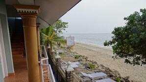 A beachside balcony with a view of the ocean, a sign indicating a beach resort, and outdoor seating with umbrellas. - Sealine Beach Resort (Kochi)