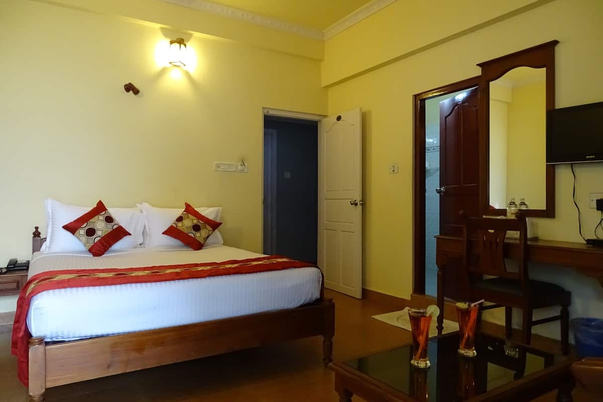 A hotel room with a bed, bedside table, mirror, and a door leading to another room.