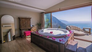 Un baño con una bañera grande, un espejo, un armario de madera y vistas a un paisaje montañoso.
