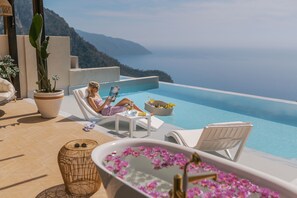 A poolside area with a lounge chair, a small table, and a bathtub with flowers. - Lissiya Hotel - Boutique Class (Fethiye)