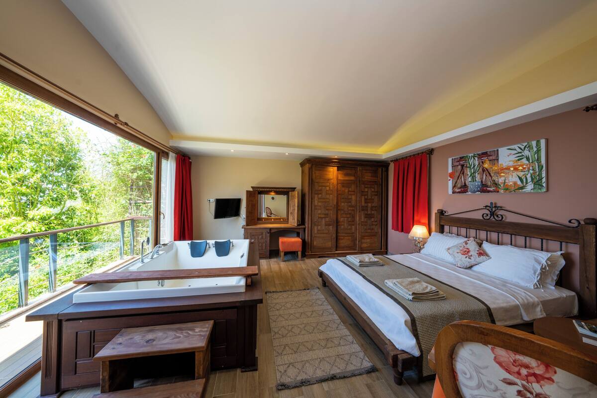 A bedroom with a bed, a desk, a chair, a window, and a painting on the wall.