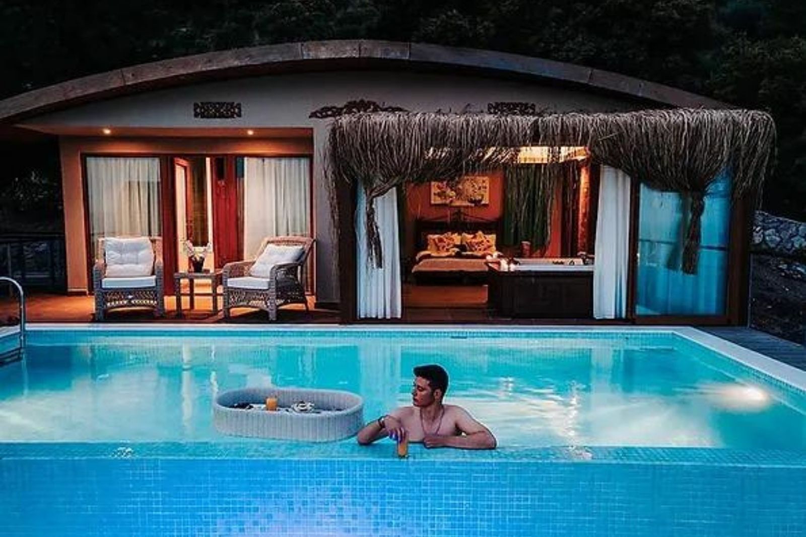 A swimming pool with lounge chairs and a covered seating area.