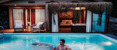 A swimming pool with lounge chairs and a covered seating area.