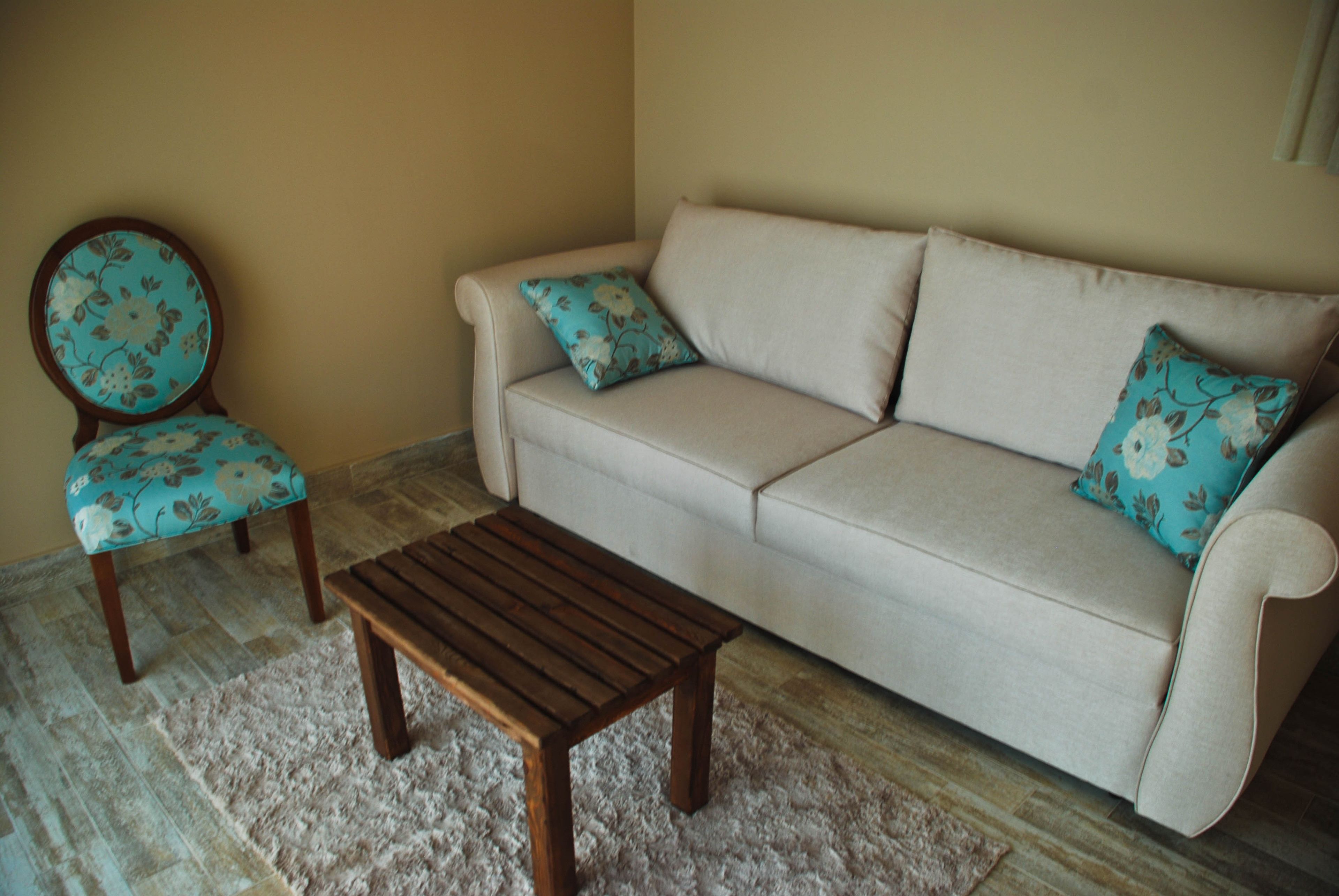 A living room with a beige sofa, two matching floral-patterned armchairs, and a wooden coffee table.