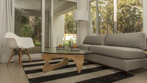 Ein modernes Wohnzimmer mit einem Glastisch, einem grauen Sofa und einem weißen Sessel.