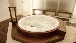 Ein Whirlpool mit Holzboden und Bedienfeld, umgeben von Fliesen und Holzverkleidung.