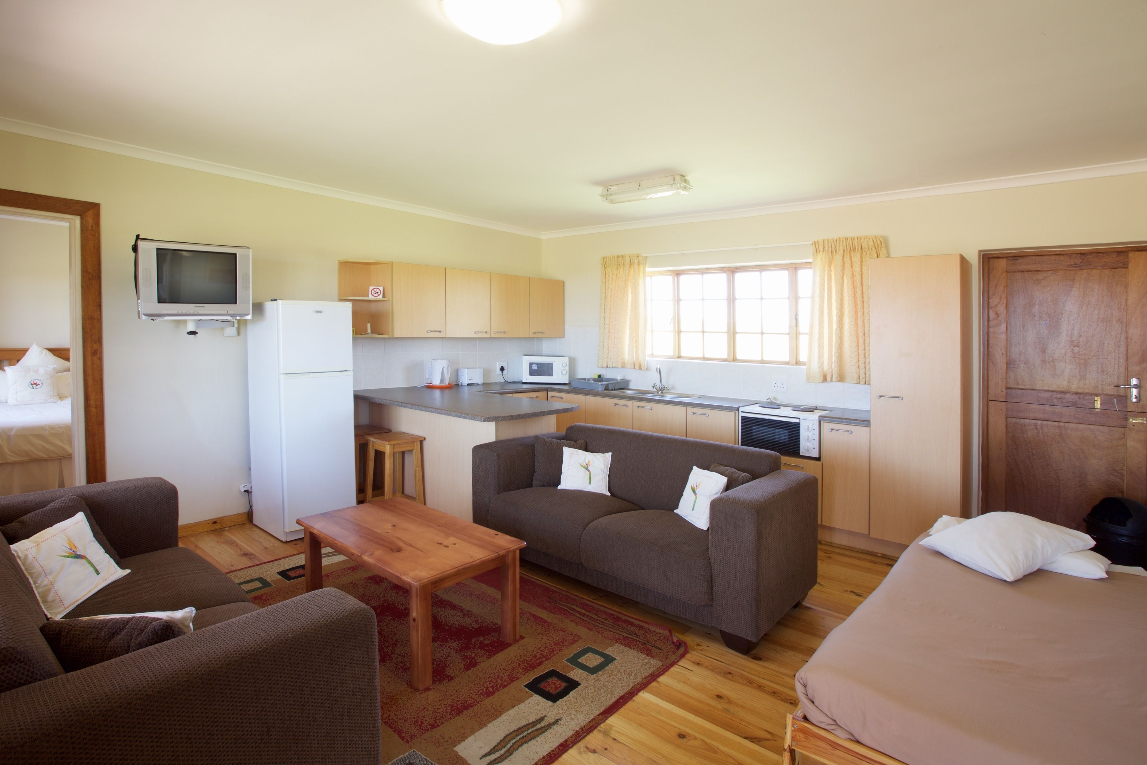 Un espacio habitable compacto con kitchenette, un sofá, una mesa pequeña y una cama.