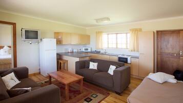 Un espacio habitable compacto con kitchenette, un sofá, una mesa pequeña y una cama.