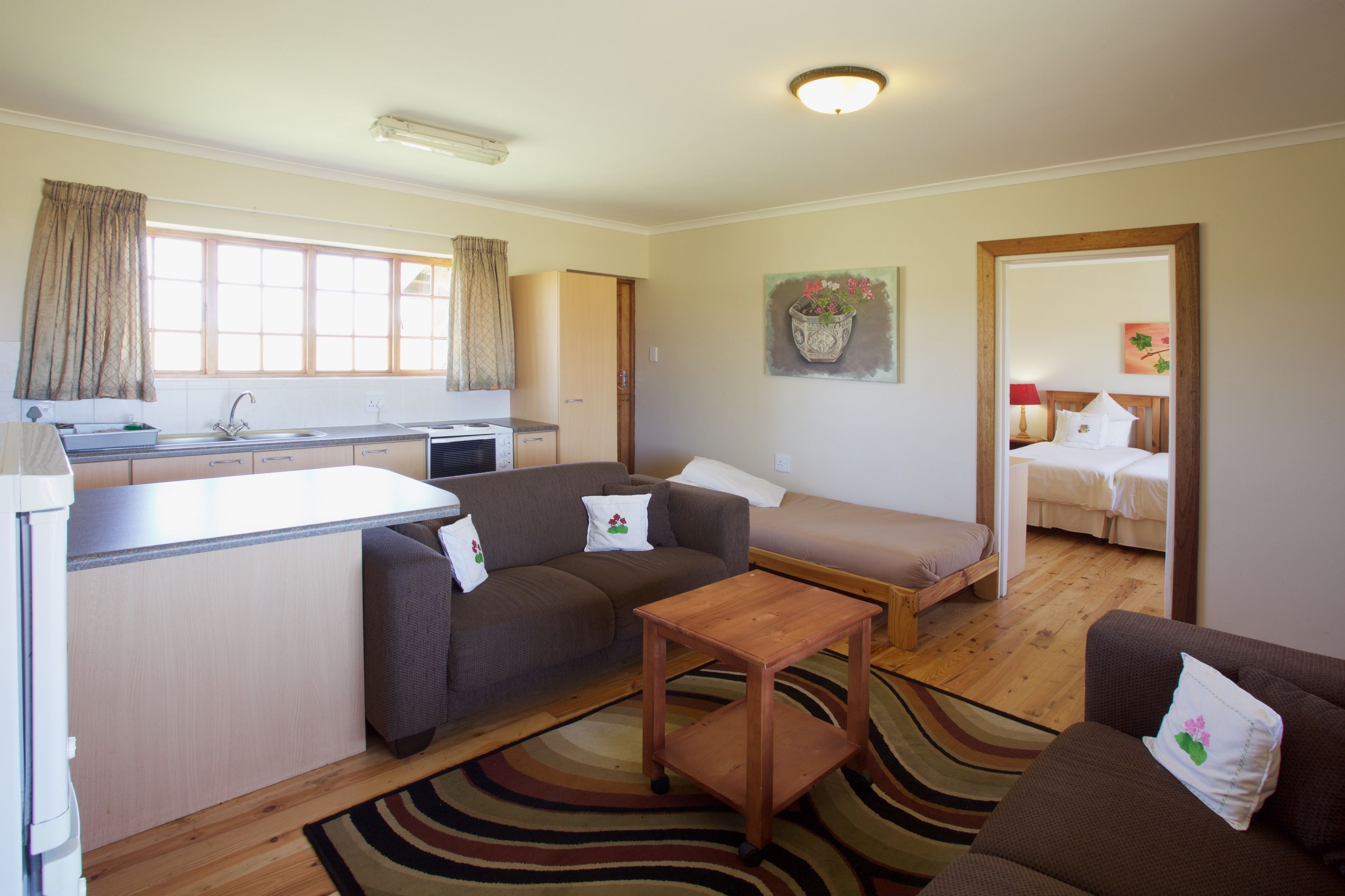 A compact living space with a kitchenette, a sofa, a small table, and a bed.