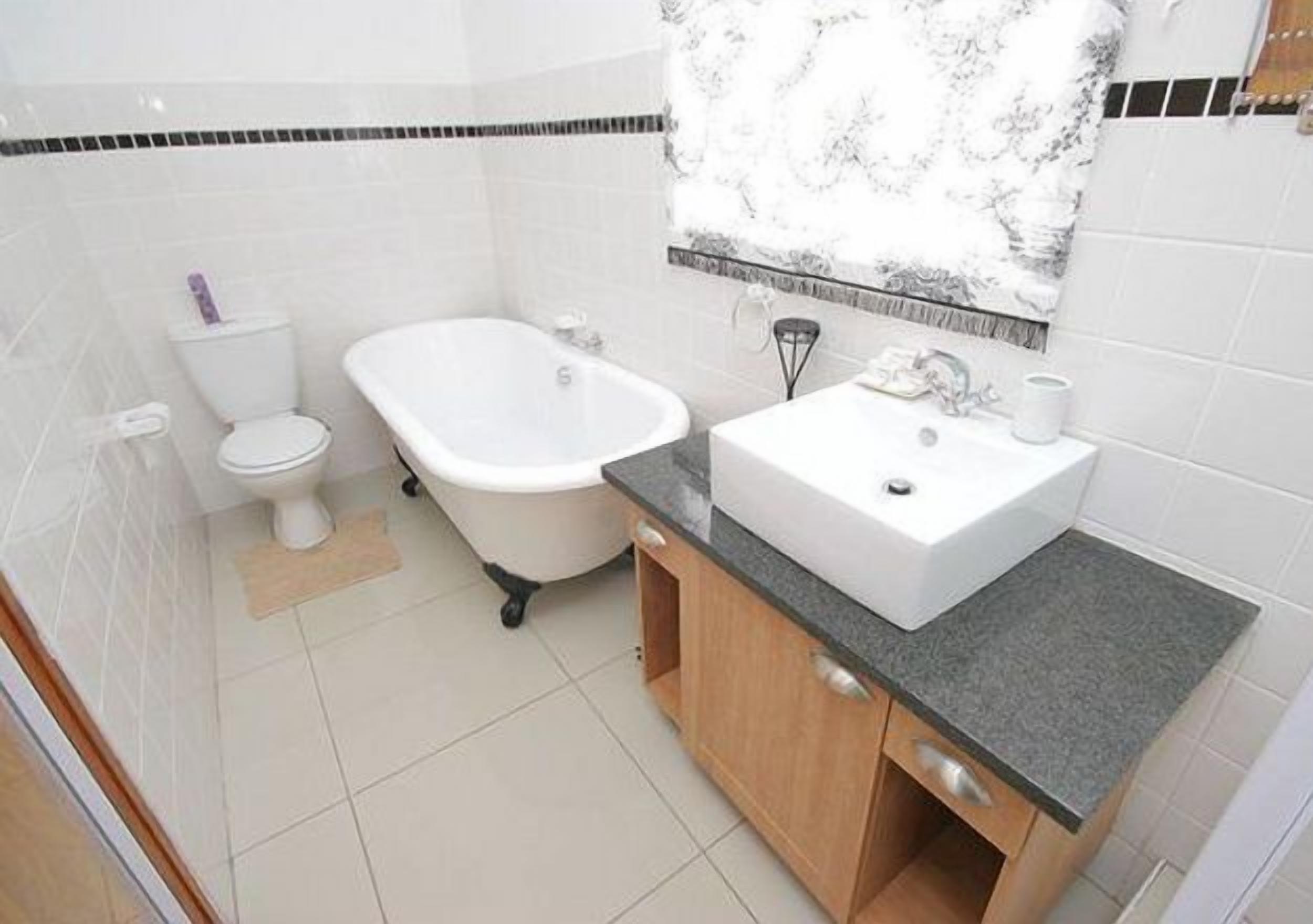 Une salle de bain comprenant des toilettes, une baignoire sur pieds et un lavabo avec un meuble-vasque.