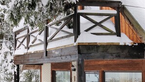 A wooden cabin with a balcony, a bench, and wicker chairs. - Traveland Butique Resort Poiana Brasov (Brasov)